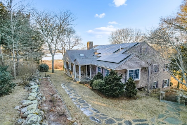 exterior space featuring solar panels, a chimney, and a shingled roof