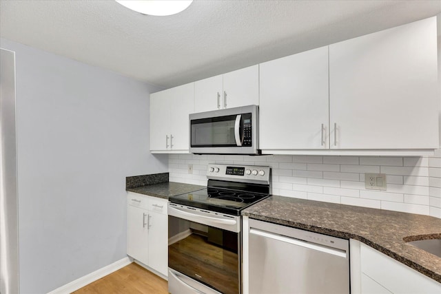2124 Heatherwood, Yarmouth Port, MA 02675 - kitchen featuring appliances with stainless steel finishes, light wood-style floors, tasteful backsplash, white cabinetry, and dark stone countertops