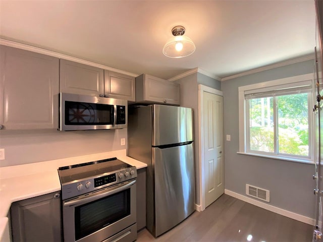 232 Eaton Ln, Brewster, MA 02631 - kitchen featuring appliances with stainless steel finishes, gray cabinets, light countertops, wood finished floors, and ornamental molding