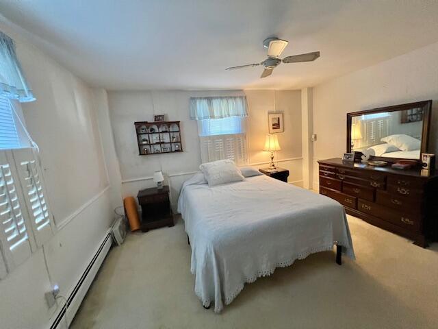 bedroom featuring ceiling fan, light colored carpet, and baseboard heating