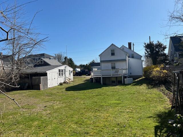 rear view of house featuring a yard, an outdoor structure, and a shed