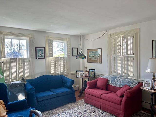 living room featuring a wainscoted wall, baseboard heating, and wood finished floors