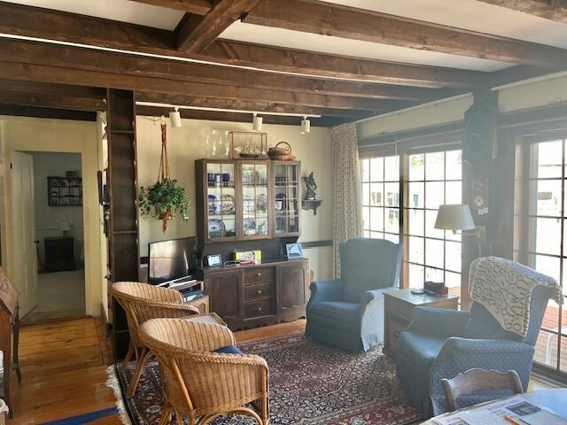 sitting room featuring beam ceiling and wood finished floors