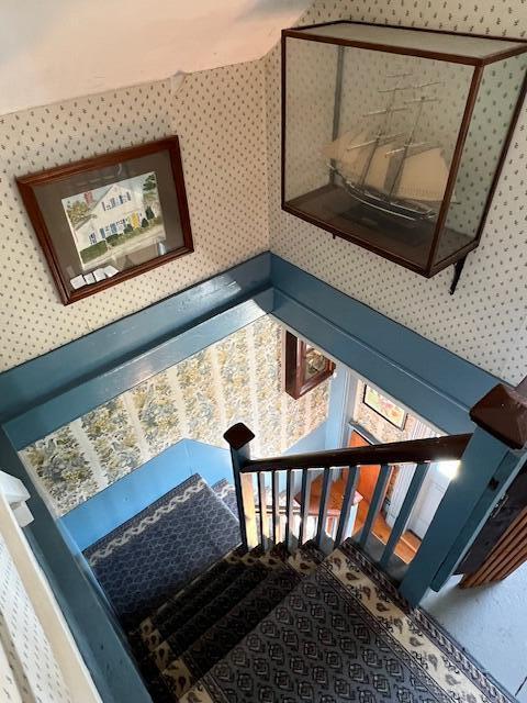 stairs featuring wallpapered walls