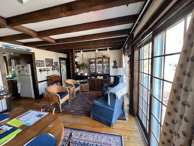 living area with wood-type flooring and beamed ceiling