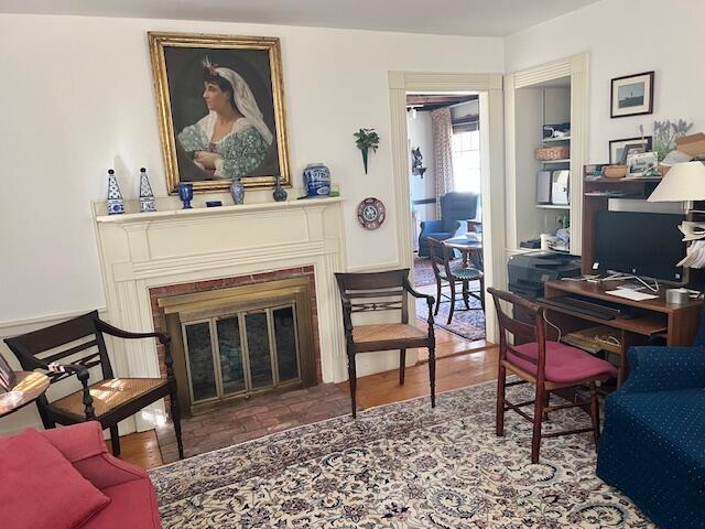office area with a glass covered fireplace and wood finished floors
