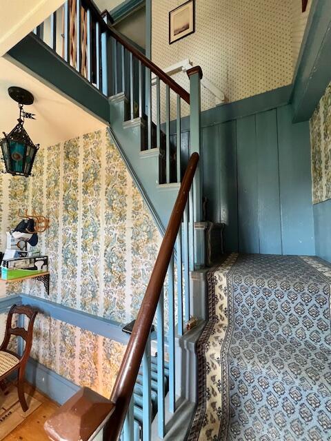 stairs with wallpapered walls and a towering ceiling