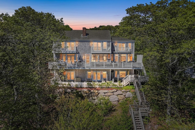 38 Captain Baker Rd, Brewster, MA 02631 - back of property at dusk with stairs, a balcony, and a chimney