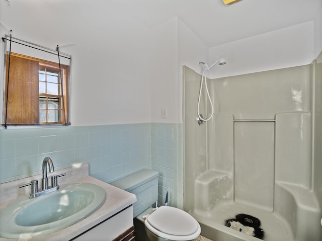 bathroom with toilet, a shower, vanity, and tile walls