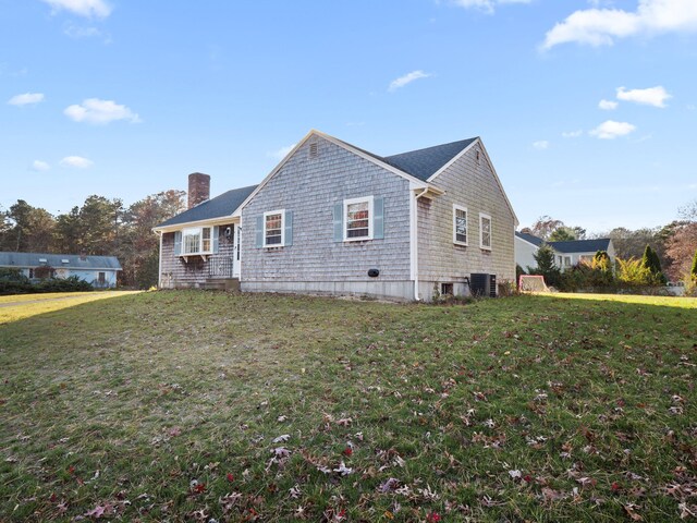 view of side of home featuring a lawn and central AC