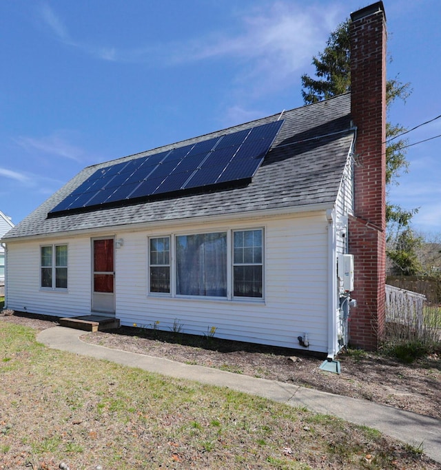 885 Sandwich Rd, Hatchville, MA 02536 - view of front of property with fence, a chimney, roof with shingles, and solar panels