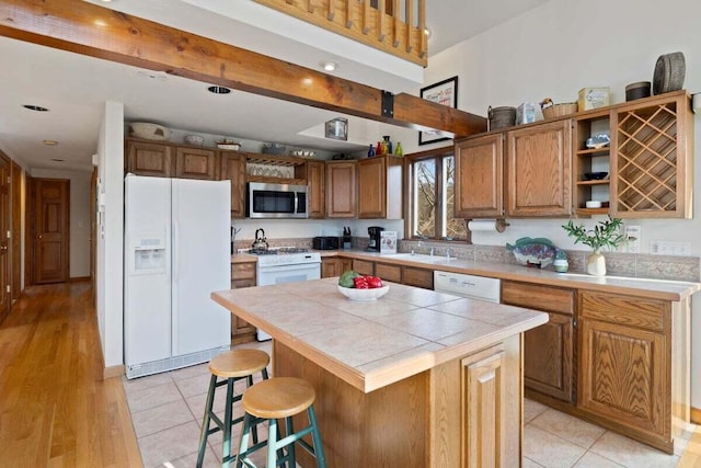 63 Swift Ln, Brewster, MA 02631 - kitchen featuring white appliances, open shelves, a center island, a breakfast bar area, and brown cabinets