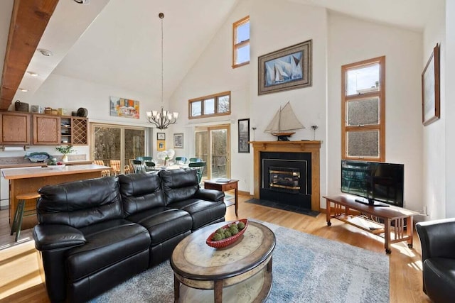 63 Swift Ln, Brewster, MA 02631 - living room with light wood-type flooring, a chandelier, high vaulted ceiling, and a fireplace with flush hearth