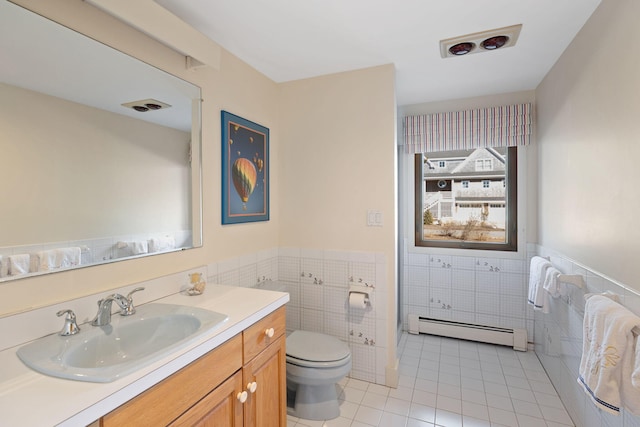 bathroom featuring toilet, a baseboard radiator, tile patterned floors, vanity, and tile walls