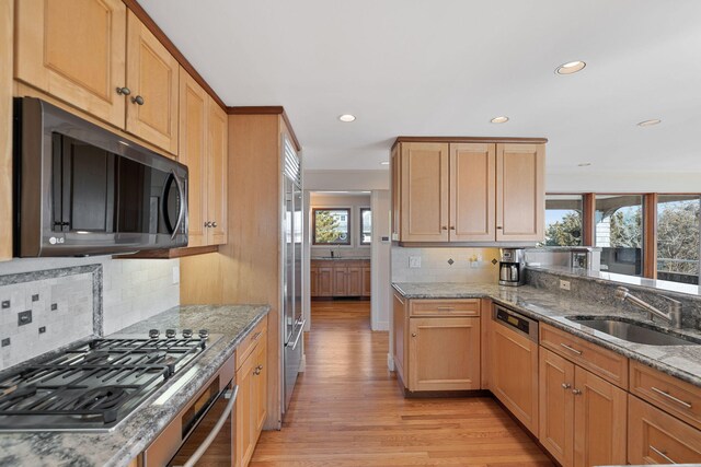 kitchen featuring stainless steel appliances, a sink, and light stone countertops