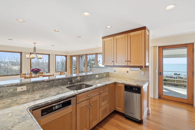 kitchen with a peninsula, a water view, a sink, hanging light fixtures, and dishwasher