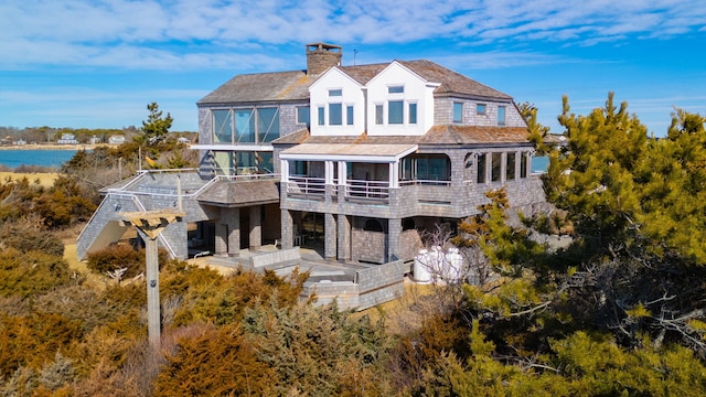 rear view of house featuring a chimney, a water view, and a balcony