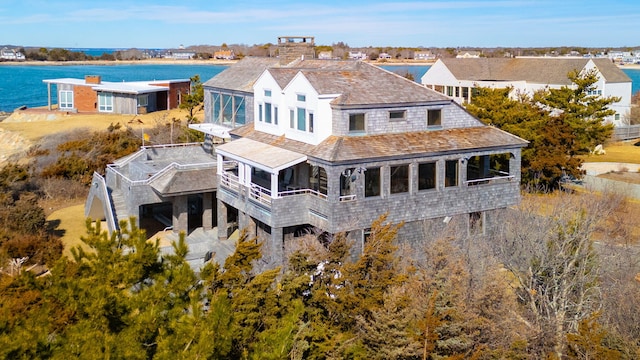 back of property with a sunroom and a water view