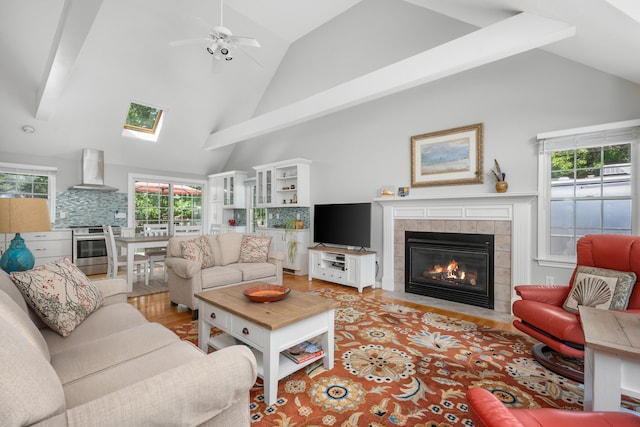 64 Manitoba Rd, Mashpee, MA 02649 - living area featuring a tiled fireplace, light wood-type flooring, ceiling fan, high vaulted ceiling, and a skylight