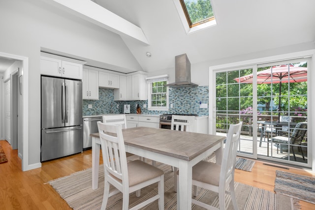 64 Manitoba Rd, Mashpee, MA 02649 - kitchen featuring appliances with stainless steel finishes, island range hood, white cabinets, a skylight, and light wood-type flooring