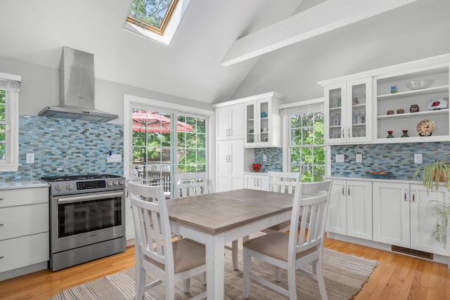 64 Manitoba Rd, Mashpee, MA 02649 - kitchen featuring wall chimney range hood, stainless steel gas range, vaulted ceiling, backsplash, and a skylight