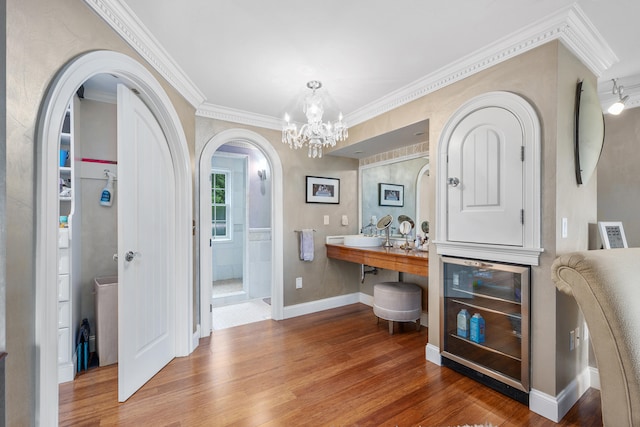 350 Plum St, West Barnstable, MA 02668 - entrance foyer with beverage cooler, arched walkways, wood finished floors, a chandelier, and crown molding