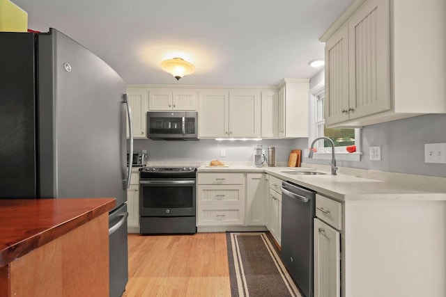 566 County Rd, Pocasset, MA 02559 - kitchen with stainless steel appliances, light wood finished floors, white cabinets, and light countertops