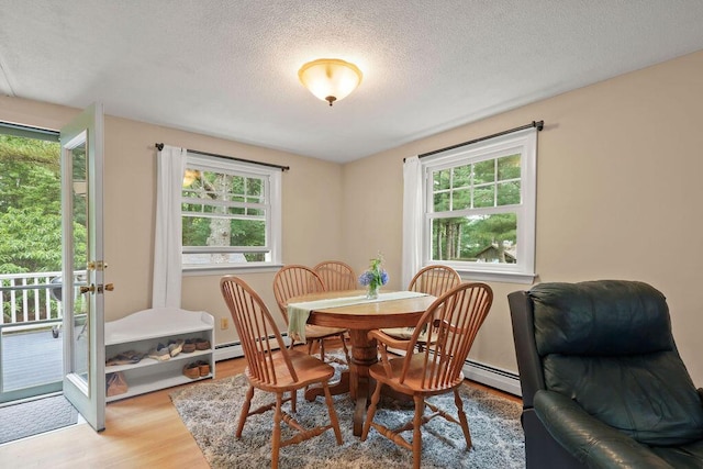 566 County Rd, Pocasset, MA 02559 - dining room with plenty of natural light, wood finished floors, a baseboard heating unit, and a textured ceiling