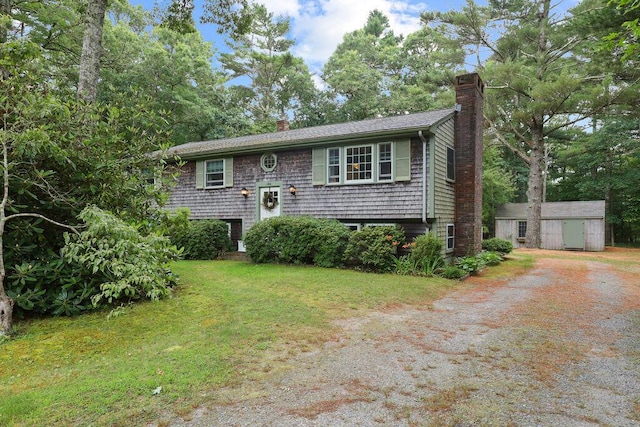 566 County Rd, Pocasset, MA 02559 - bi-level home featuring a chimney, dirt driveway, a front lawn, and an outbuilding