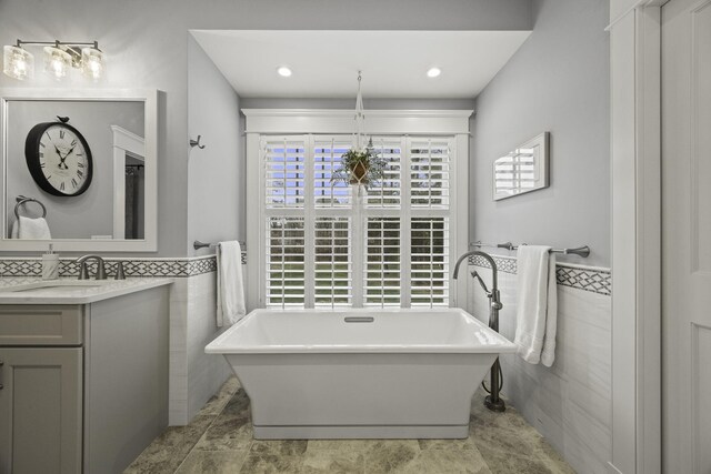 5 Jakes Ln, Brewster, MA 02631 - bathroom featuring tile walls, a freestanding bath, wainscoting, and vanity