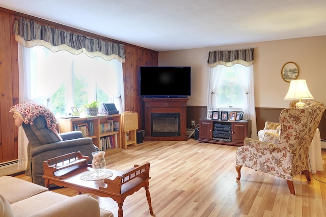 103 Moco Rd, West Barnstable, MA 02668 - living area featuring a glass covered fireplace, light wood-style floors, a baseboard heating unit, wooden walls, and wainscoting