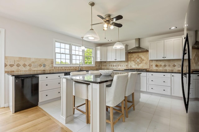 14 Kendrick Ave, Wellfleet, MA 02667 - kitchen with wall chimney exhaust hood, dark countertops, black appliances, a ceiling fan, and white cabinetry