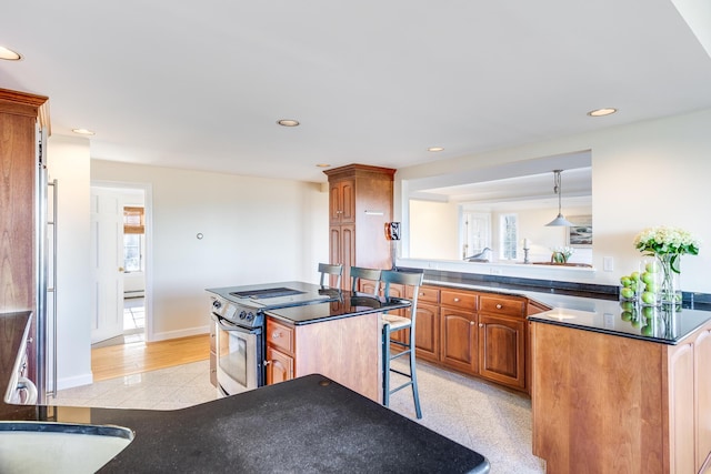 kitchen featuring a breakfast bar, appliances with stainless steel finishes, a center island, decorative light fixtures, and kitchen peninsula