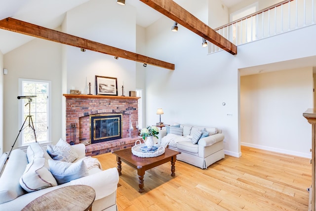 living room featuring high vaulted ceiling, a fireplace, light hardwood / wood-style floors, and beamed ceiling