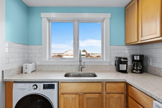 kitchen with a sink, decorative backsplash, and washer / dryer