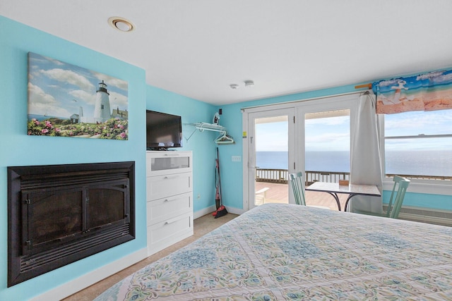 bedroom with access to exterior, a glass covered fireplace, multiple windows, and baseboards