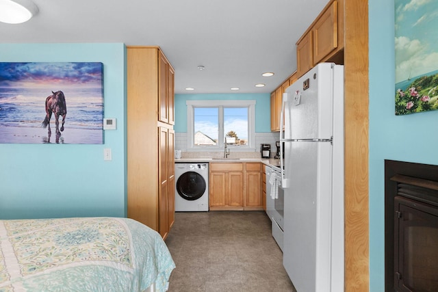 kitchen featuring washer / clothes dryer, freestanding refrigerator, a sink, decorative backsplash, and light countertops