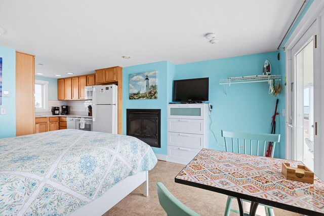 bedroom featuring recessed lighting, a glass covered fireplace, and freestanding refrigerator