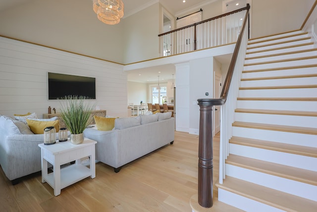 72 Woodside Dr, East Falmouth, MA 02536 - living area featuring an inviting chandelier, light wood-style floors, crown molding, a towering ceiling, and stairs