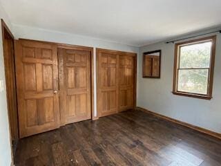 unfurnished bedroom with dark wood-type flooring and two closets