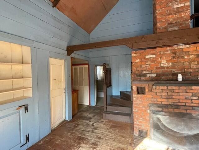 unfurnished living room with vaulted ceiling and wooden walls