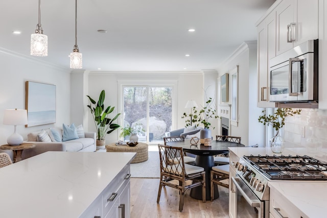 213 N Falmouth Hwy Unit 5B, North Falmouth, MA 02556 - kitchen featuring appliances with stainless steel finishes, ornamental molding, light wood finished floors, light stone counters, and white cabinetry