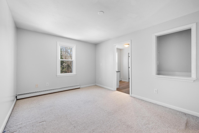 carpeted spare room featuring a baseboard heating unit and baseboards