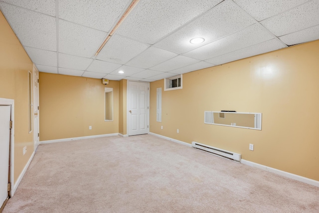 finished basement with a drop ceiling, baseboards, baseboard heating, and carpet floors