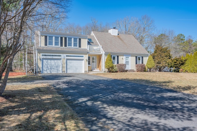 view of front of house featuring a balcony, an attached garage, a shingled roof, a chimney, and aphalt driveway