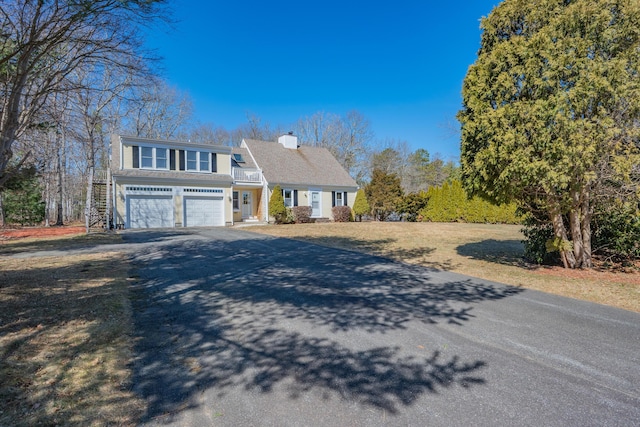 view of front of property with aphalt driveway, an attached garage, and a chimney