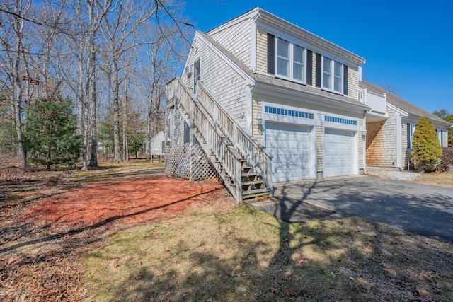 view of front of home with driveway, a shingled roof, stairs, and a garage