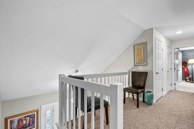 corridor featuring lofted ceiling and carpet flooring