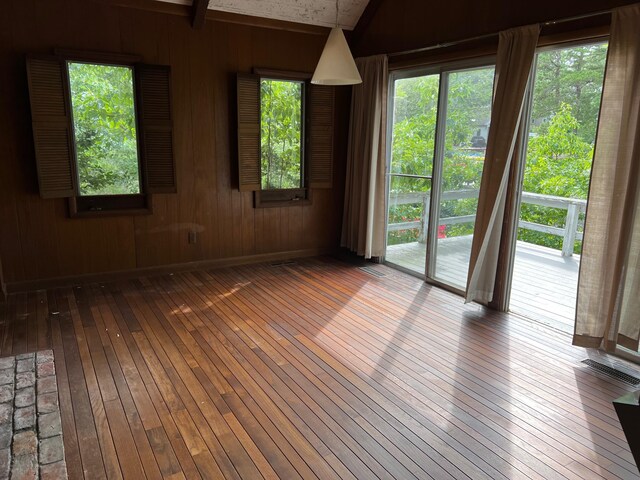 unfurnished room with wood walls and hardwood / wood-style flooring