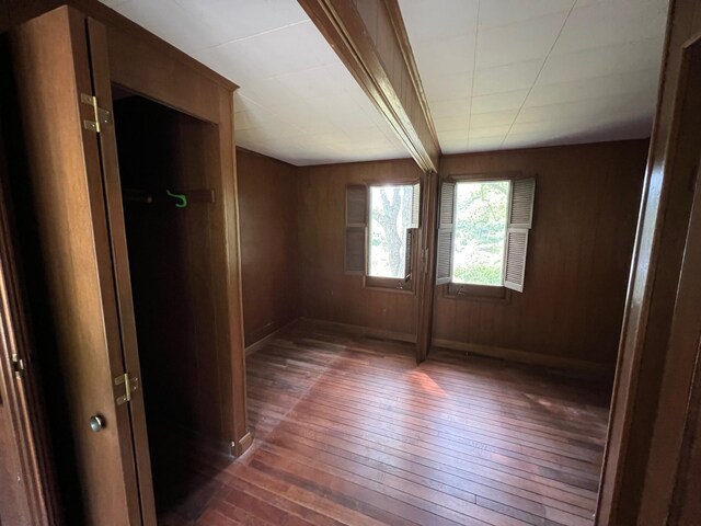 unfurnished room with dark wood-type flooring and wooden walls